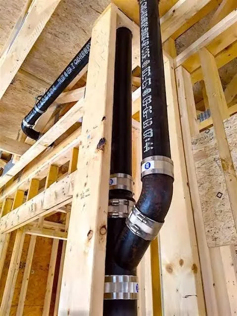 Cast iron drain stack replaced with PVC piping, fittings, and metal support straps in wall cavity
