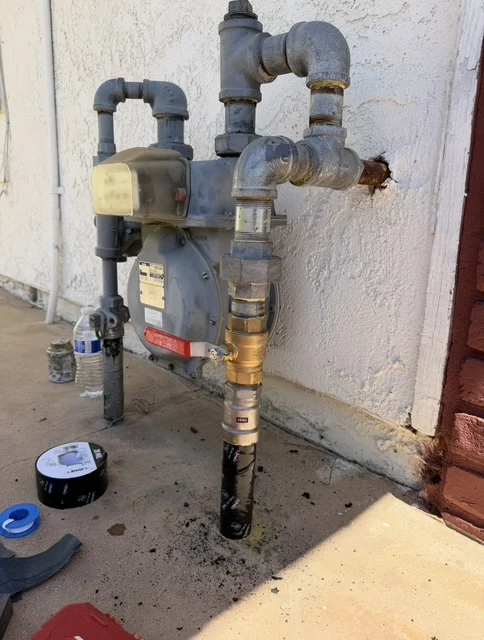 Water meter installation with PVC pipes, brass valves, and pressure regulators on exterior wall